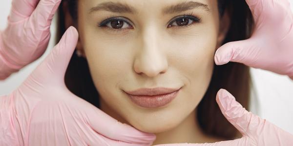 Hands in gloves on face undertaking treatments